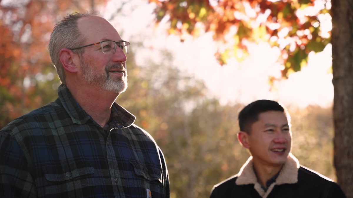 Two men in conversation outdoors during golden hour, surrounded by autumn foliage during a Spiracle Media video shoot.